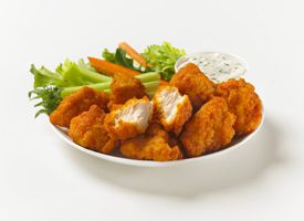 A plate of chicken and vegetables with ranch.
