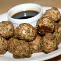 A plate of meatballs and sauce on the table.