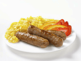 A plate of food with sausage, corn and strawberries.