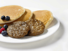 A plate of pancakes and sausage patties on top.