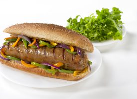 A sausage sandwich on a bun with lettuce and mustard.